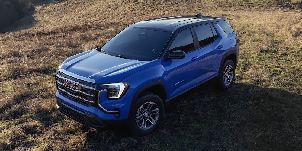 A bright blue 2026 GMC Terrain SUV parked in a field