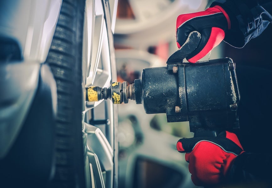 A technician working on a vehicle's tire