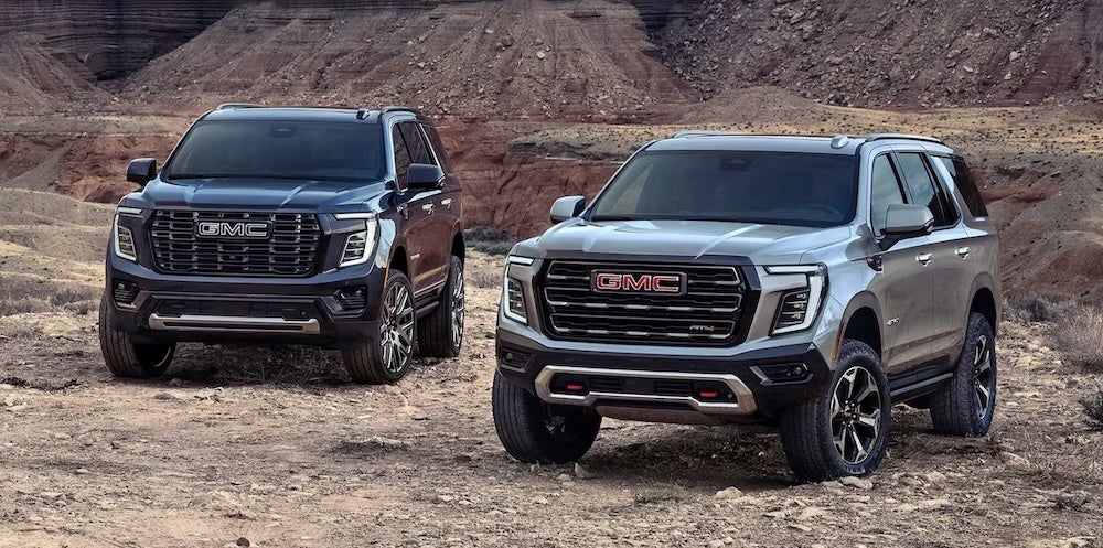 Two GMC SUVs parked in the desert