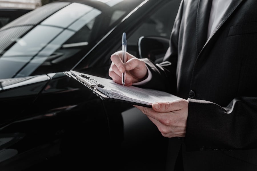 A car dealer filling out paperwork beside a car